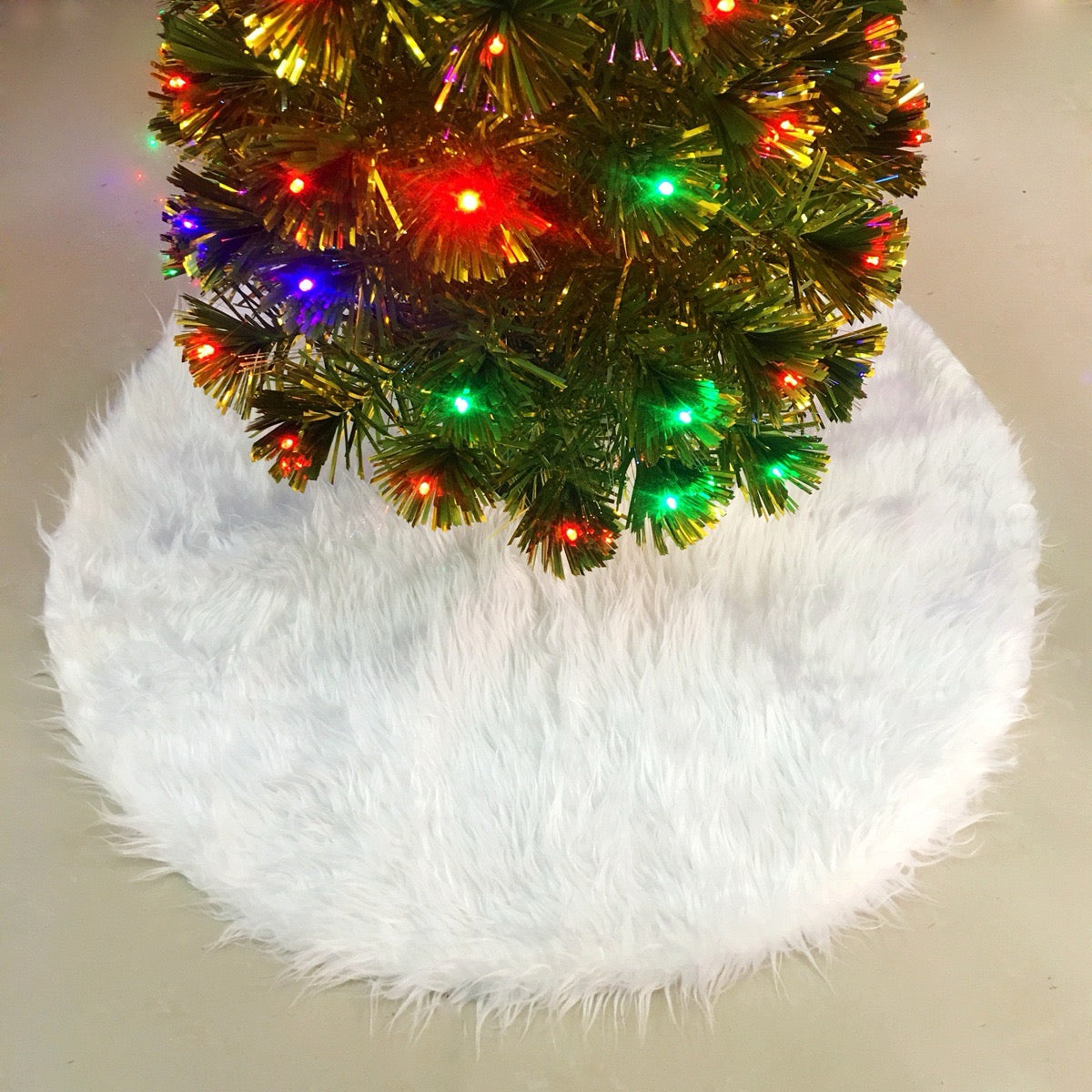 White plush Christmas tree skirt under a lit Christmas tree